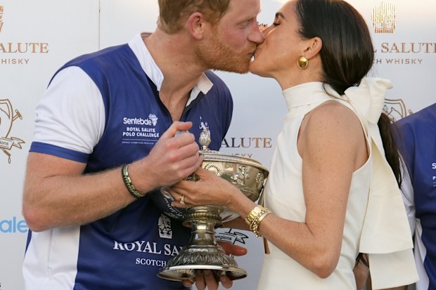 Prince Harry and Meghan Markle, Duchess of Sussex, kiss as she presents his polo team with the trophy for winning the Royal Salute Polo Challenge to Benefit Sentebale, Friday, April 12, 2024, in Wellington, Florida