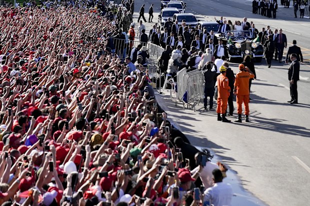 Supporters wave as Luiz Inacio Lula da Silva arrives on an open car to the Planalto Palace after he was sworn in as new president in Brasilia, Brazil, Sunday, Jan. 1, 2023. (AP Photo/Silvia Izquierdo)