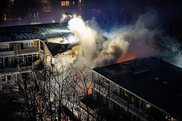 Firemen try to douse a fire following an explosion at a residential building in The Hague