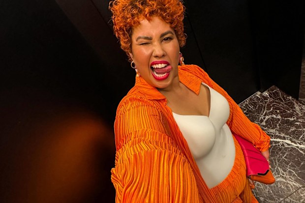 April Helene-Horton poses in a bright orange set.