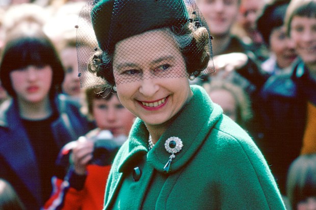 Worcester, England, in 1980, Queen Elizabeth wears the Round Cambridge Emerald brooch, which belonged to her great-grandmother, Princess Mary Adelaide of Cambridge, Duchess of Teck.