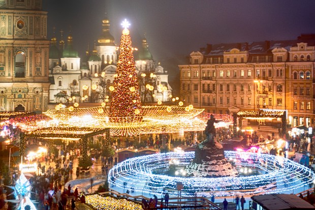Crowds of people celebrate the New Year around the Christmas tree with the St. Sofia Cathedral in the background in Kyiv, Ukraine, Friday, Dec. 31, 2021