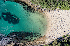 Panoramic aerial bird's eye view of Shelly Beach at the southeastern end of Manly, a beachside suburb of Sydney, New South Wales, Australia. Hot summer day with many people on the beach enjoying sun.