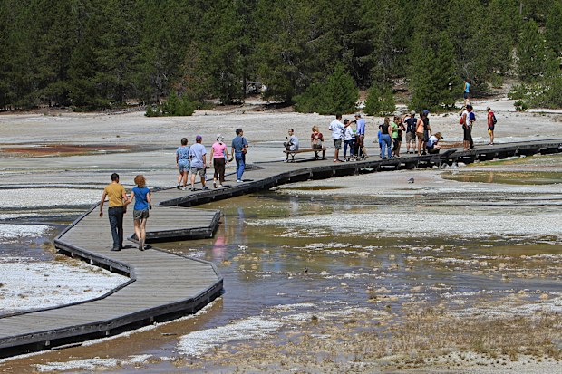 Visitors walk on the boardwalk in the Norris Geyser Basin in Yellowstone National Park, Wyoming,