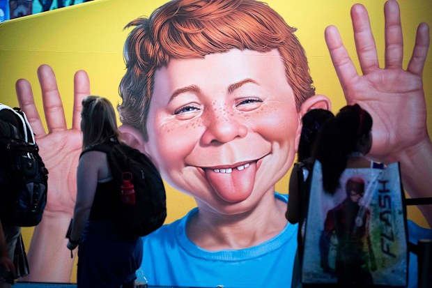 The face of Alfred E. Neuman is framed by attendees at the DC booth during the first day of Comic-Con International at the San Diego Convention Center in San Diego.