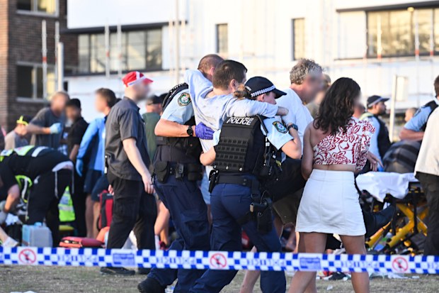Police and bystanders carry a wounded victim from the Bondi mass shooting.
