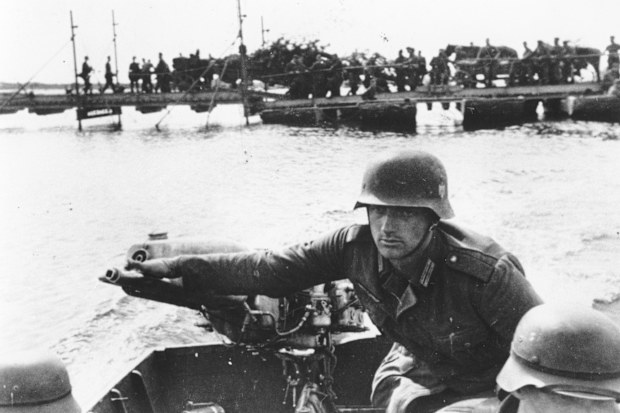 As the German invasion of the Ukraine continues, a German soldier is seen as he operates the outboard engine of a motorboat while crossing the Dnieper river, in September 1941. Standing in the  background are troops and military vehicles awaiting their turn. AP Photo)