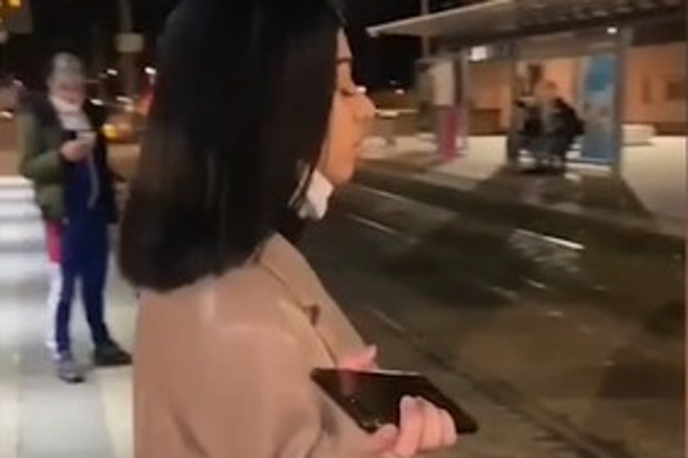 French woman, Sarah, standing on a train platform as two men heckle her.