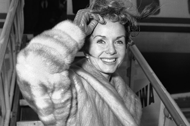 Screen actress Debbie Reynolds is a pretty wind-blown portrait as she boards airliner on March 6, 1959 in New York for Spain where she will film a new picture. She had flown in from California earlier in the day and contended with many questions about her divorced husband Eddie Fisher?s romance with Elizabeth Taylor. Said she: ?I wish them all happiness. That?s what we all want isn?t it?? (AP Photo/John Rooney)