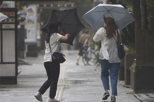 People holding umbrellas struggle with the strong wind as a typhoon approaches in Kagoshima, western Japan.