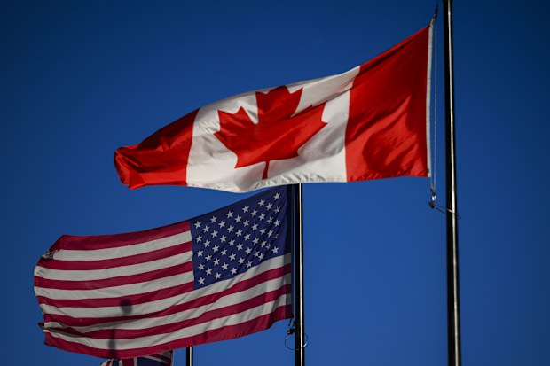 The flags of Canada and the United States fly outside a hotel in downtown Ottawa, on Saturday, Feb. 1, 2025. (Justin Tang/The Canadian Press via AP)