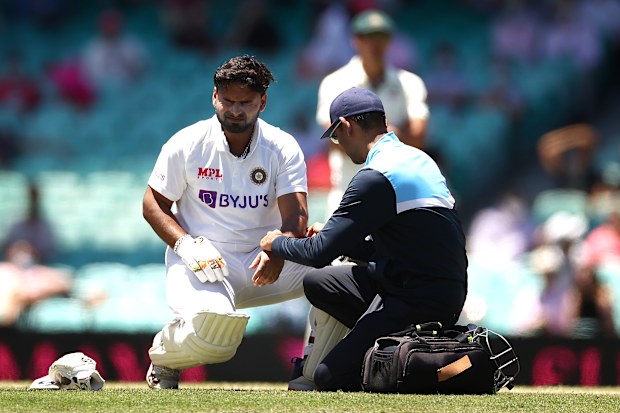 Rishabh Pant of India reacts after being struck by a delivery from Pat Cummins of Australia.