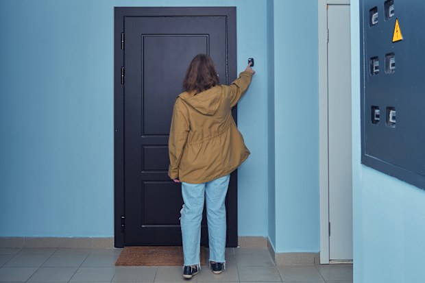 Person ringing doorbell in apartment hallway. Indoor photography for residential building, safety, and security concepts