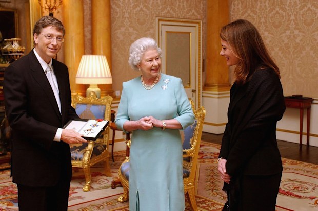 Queen Elizabeth II presents Bill Gates with an honorary knighthood in 2005, as his wife Melinda watches on.