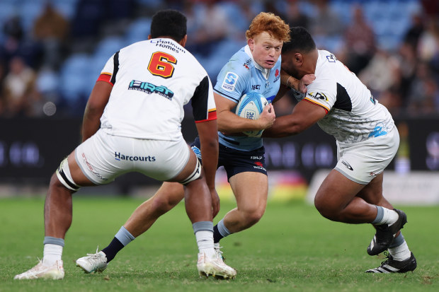 Tane Edmed of the Waratahs is challenged during the round ten Super Rugby Pacific match against the Chiefs.