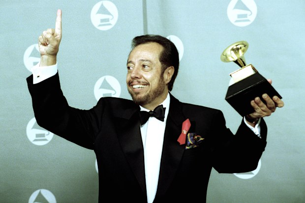 FILE - Sergio Mendes holds up his Gramophone trophy at the Grammy Awards show held at the Shrine Auditorium in Los Angeles, on Feb. 24, 1993. (AP Photo/Reed Saxon, File)
