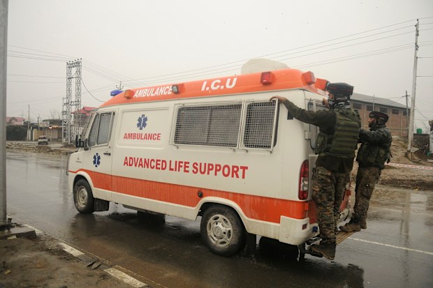 Soldiers hang on to an ambulance carrying bodies 