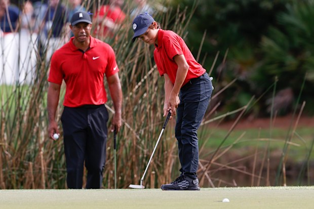 Charlie Woods sinks a putt on the second green while being watched by father Tiger Woods during the second round of the PNC Championship.