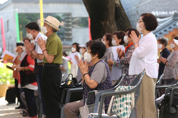 People wearing face masks to help protect against the spread of the coronavirus pray while maintaining social distancing during a service at the Chogyesa temple in Seoul, South Korea.