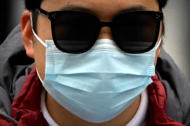 A commuter wearing a face mask rides a scooter along a street in the central business district in Beijing, Friday, Oct. 28, 2022. 