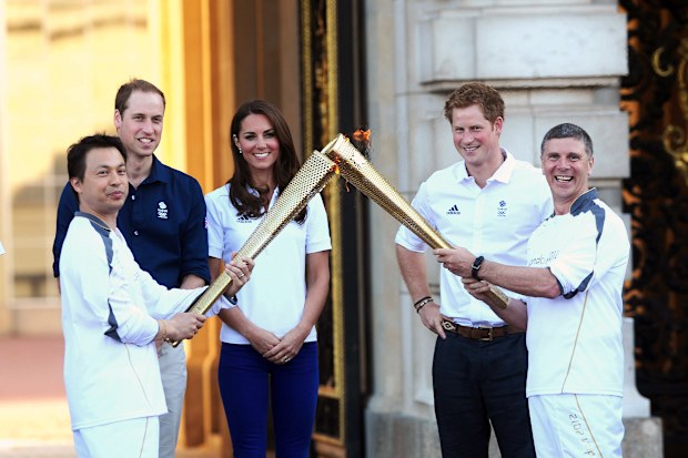 Prince William,  Duke of Cambridge, Catherine, Duchess of Cambridge and Prince Harry watch Wai-Ming hand over the London 2012 Olympic Torch to John Hulse during a visit to Buckingham Palace during Day 69 of the London 2012 Olympic Torch Relay on July 26, 2012.