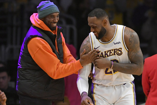 LeBron James of the Los Angeles Lakers has a moment on the sideline with former Laker Kobe Bryant.