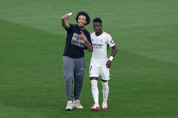 A pitch invader attempts to take a selfie on a mobile phone with Vinicius Junior of Real Madrid.