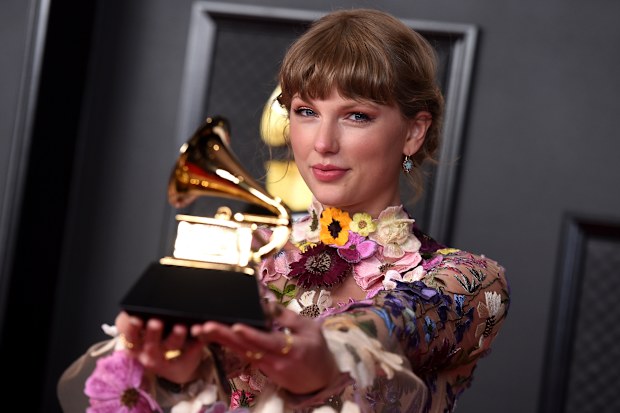 Taylor Swift poses in the press room with the award for album of the year for "Folklore" at the 63rd annual Grammy Awards at the Los Angeles Convention Center on Sunday, March 14, 2021 
