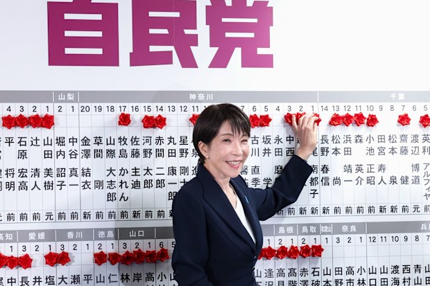 Japan's Prime Minister Sanae Takaichi, leader of the ruling Liberal Democratic Party (LDP), places a red paper rose on the name of an elected candidate at the LDP headquarters on general election day in Tokyo, Japan, February 8, 2026.