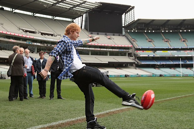 Ed Sheeran kicks a football at the Melbourne Cricket Ground.
