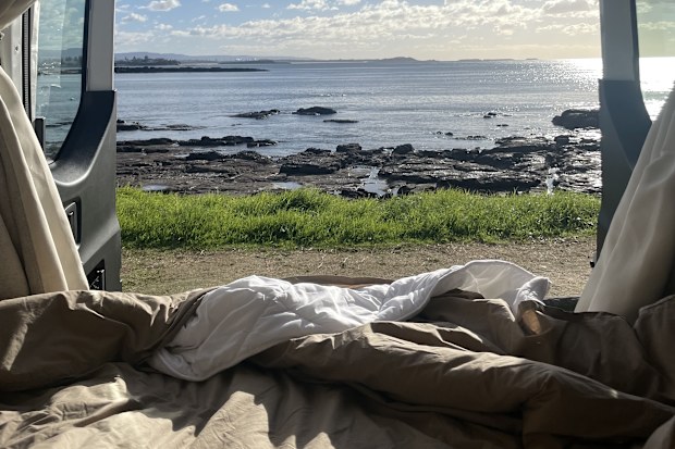 The view out the back of a caravan with blue sky and the ocean
