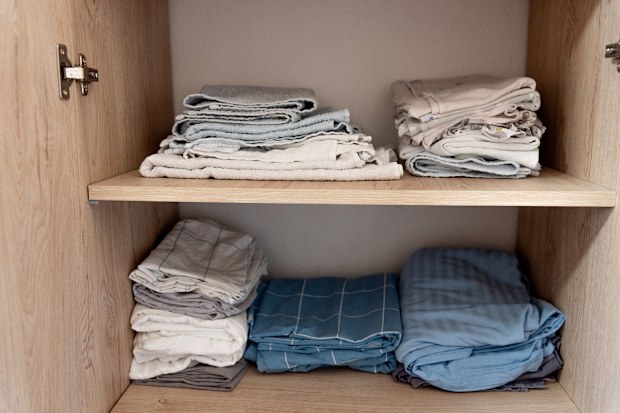 Bed linen, sheets and pillowcases and towels are neatly stacked in closet in the bedroom