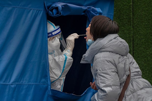 BEIJING, CHINA - MARCH 25: A health worker wears a  protective suit as she performs a nucleic acid test to detect COVID-19 at a testing site in the street on March 25, 2022 in Beijing, China. China has stepped up efforts to control a recent surge in coronavirus cases across the country, locking down the entire province of Jilin and the city of Shenyang and putting others like Shenzhen and Shanghai under restrictions. Local authorities across the country are mass testing as China tries to maintai