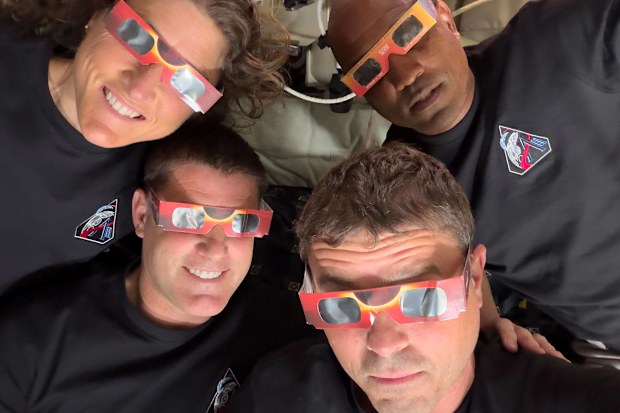 In this image provided by NASA, the Artemis II crew, counterclockwise from top left, Mission Specialist Christina Koch, Mission Specialist Jeremy Hansen, Commander Reid Wiseman, and Pilot Victor Glover pose with eclipse viewers during a lunar flyby, Monday, April 6, 2026. (NASA via AP)