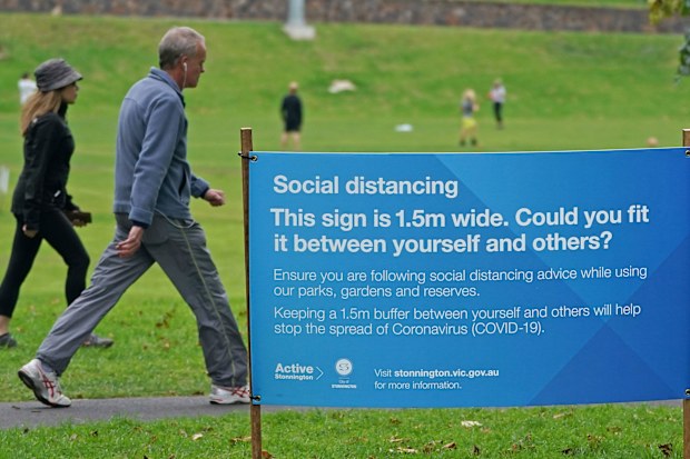 People exercise at a park which displays social distancing signage in Melbourne, Saturday, April 18, 2020.
