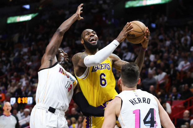 MIAMI, FLORIDA - DECEMBER 28: LeBron James #6 of the Los Angeles Lakers goes to the basket against Bam Adebayo #13 and Tyler Herro #14 of the Miami Heat during the fourth quarter of the game at FTX Arena on December 28, 2022 in Miami, Florida. NOTE TO USER: User expressly acknowledges and agrees that, by downloading and or using this photograph, User is consenting to the terms and conditions of the Getty Images License Agreement. (Photo by Megan Briggs/Getty Images)