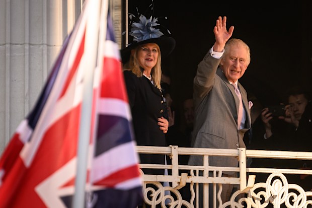 King Charles III waves from the balcony as he visits Luton Town Hall on December 6, 2022 in Luton, England 