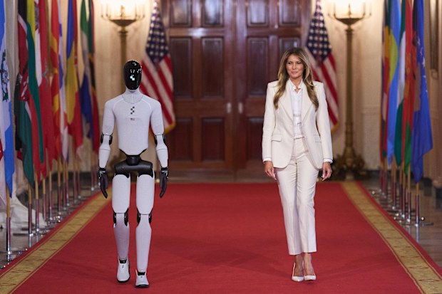Accompanied by a robot, first lady Melania Trump arrives to attend the "Fostering the Future Together Global Coalition Summit," with other first spouses, at the White House, Wednesday, March 25, 2026, in Washington. (AP Photo/Jacquelyn Martin)