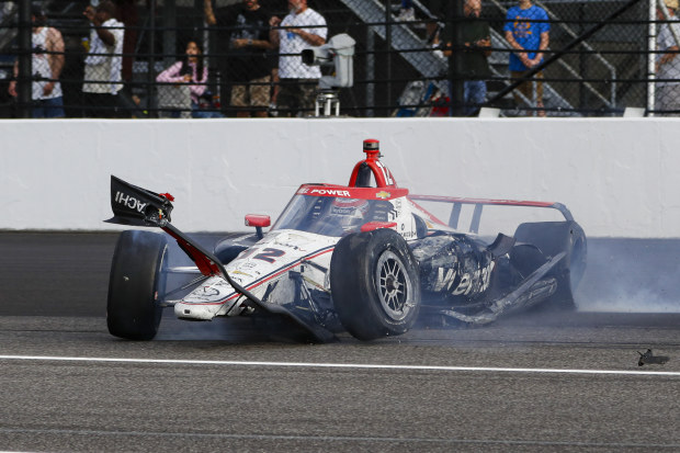 The damaged car driven by Will Power slides after hitting the wall in the first turn during the 108th Indianapolis 500.