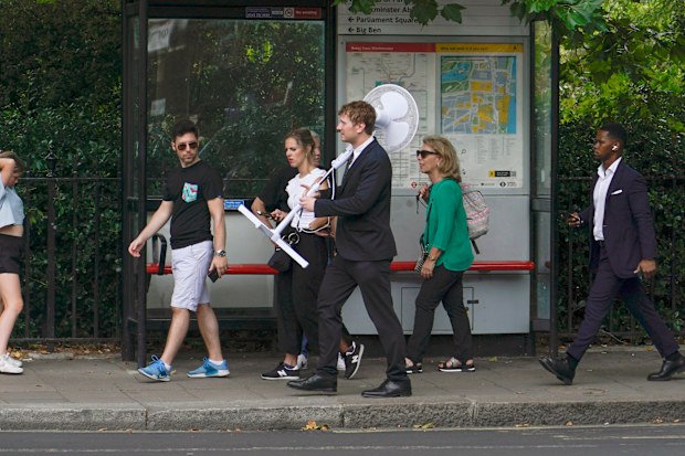 A man carries a fan as he walks outside Parliament, in London, Tuesday, July 12, 2022. 