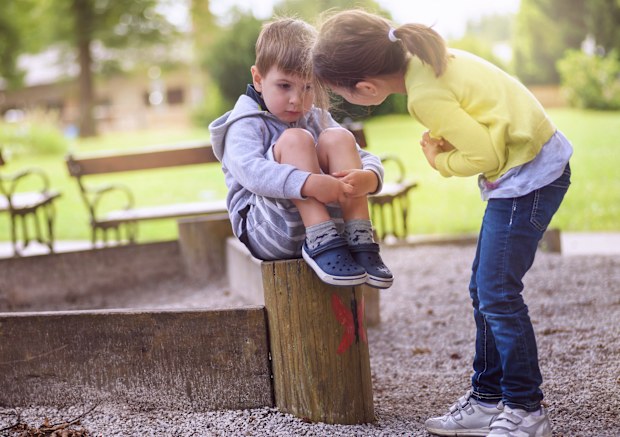 Girl Supporting Sad Boy Sitting Alone on Playground