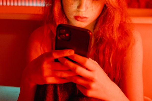 Woman cried looking at her phone in a red room.