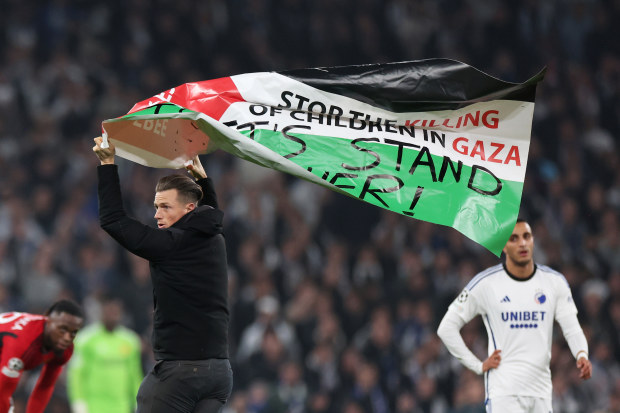 A pitch invader holds the Palestinian flag at Parken Stadium.