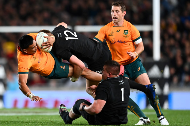 Len Ikitau of the Wallabies is tackled by Jordie Barrett of the All Blacks.