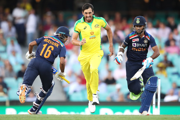 Mitchell Starc of Australia runs for the ball between Mayank Agarwal and Shikhar Dhawan.