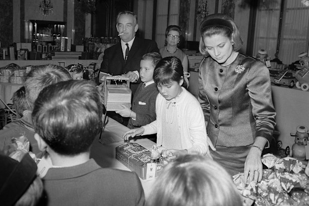 Princess Grace, Prince Rainier and their two children Albert and Stephanie participating in a toy distribution.  