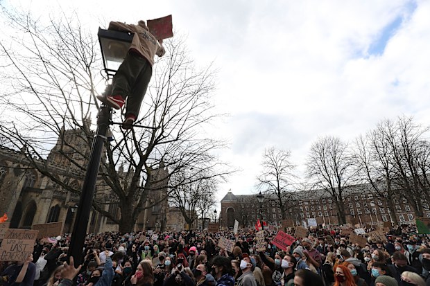 A protester climbs a lamp post as people take part in a 'Kill the Bill' protest in College Green