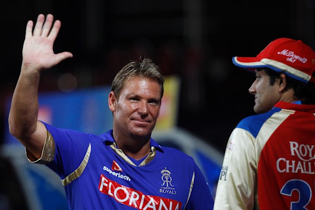 Rajasthan Royals captain Shane Warne, left, waves to his fans as rains delay the play of an Indian Premier League (IPL) cricket match between Royal Challengers Bangalore and Rajasthan Royals in Bangalore, India, on April 19, 2011.