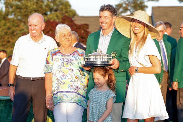 Rory McIlroy of Northern Ireland holds the trophy wearing his Green Jacket with his family his father Gerry McIlroy, his mother Rosie McIlroy his wife Erica and his daughter Poppy at the presentation after the final round of the 2026 Masters Tournament at Augusta National Golf Club on April 12, 2026 in Augusta, Georgia. 