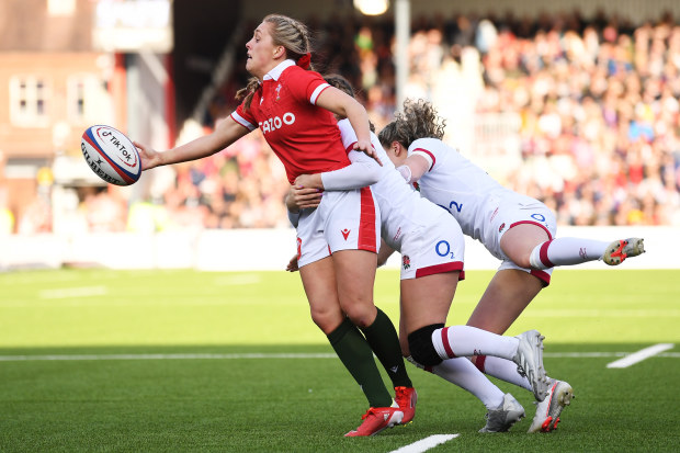 Hannah Jones of Wales offloads while being tackled by Jess Breach and Ellie Kildunne of England.